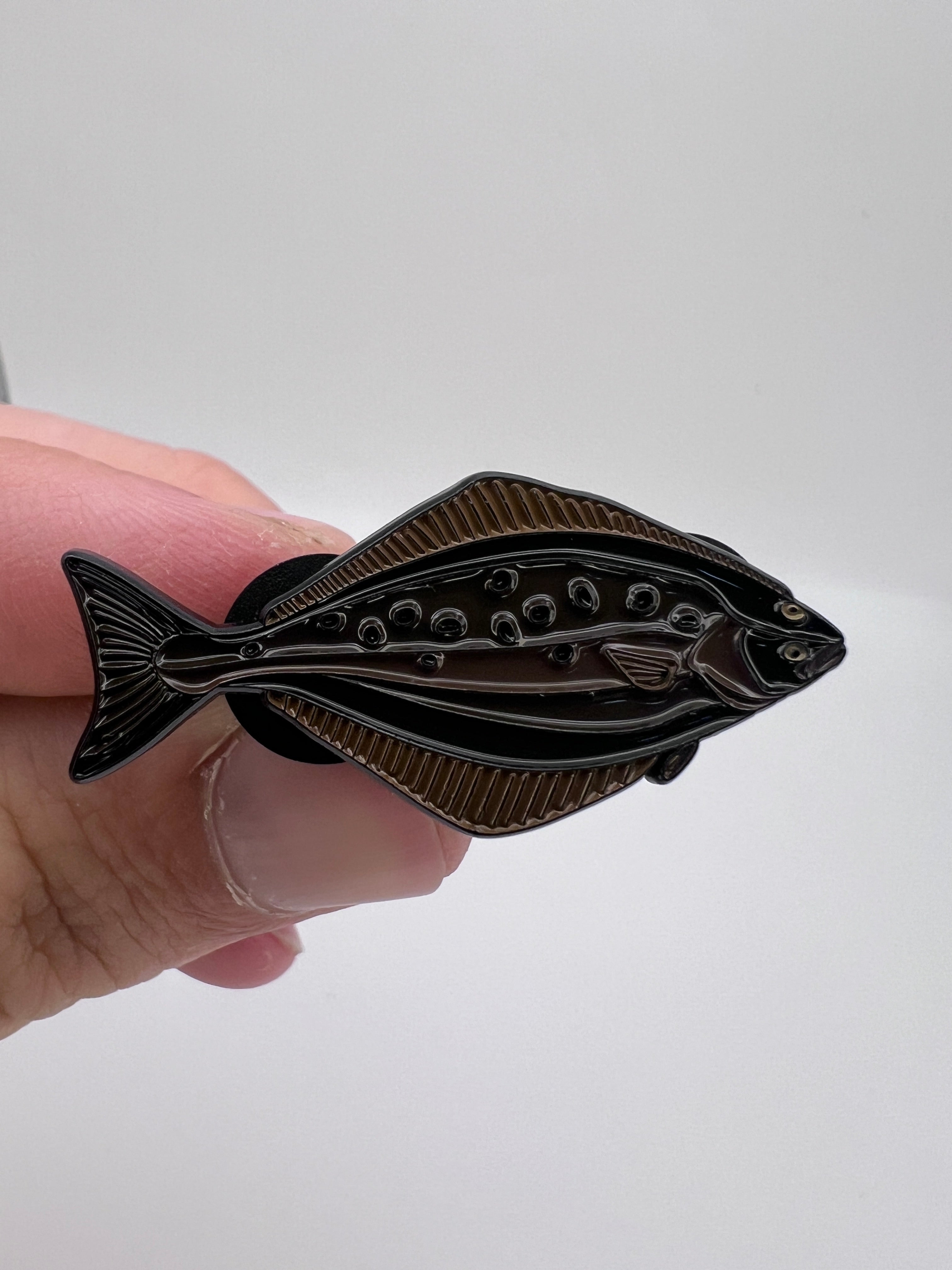 Hand holding a decorative fish-shaped object against a white background
