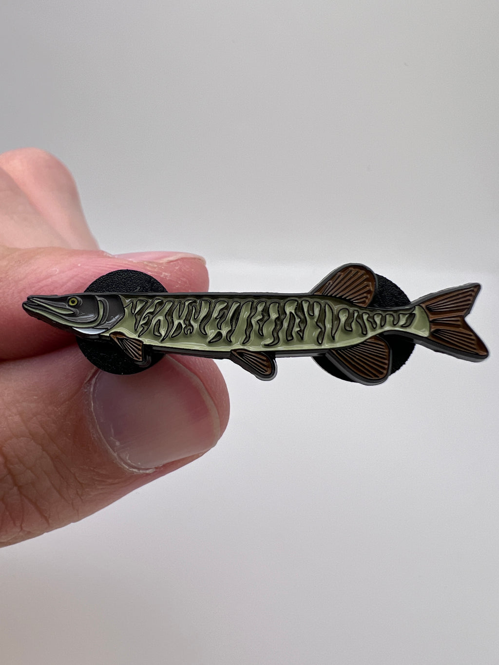 Fishing lure shaped like a fish held between fingers against a white background
