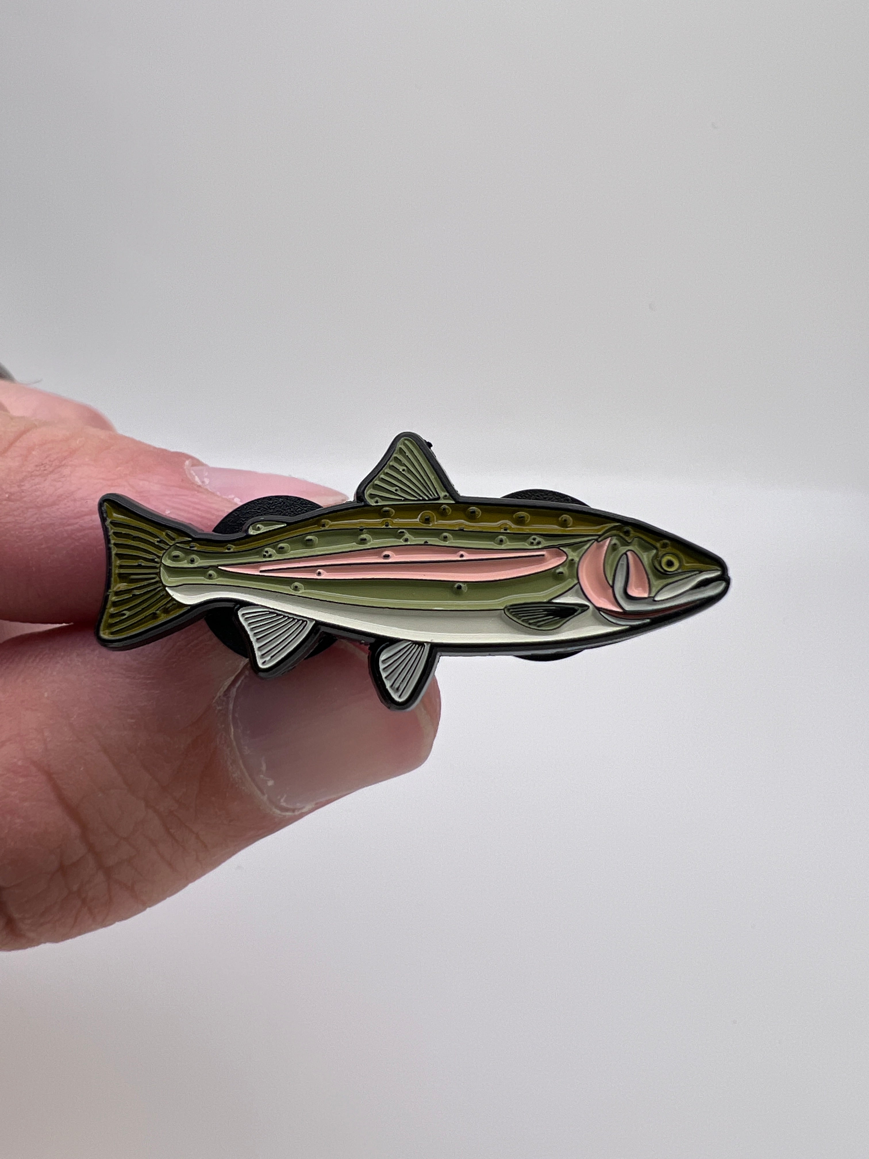 Hand holding a trout pin against a white background