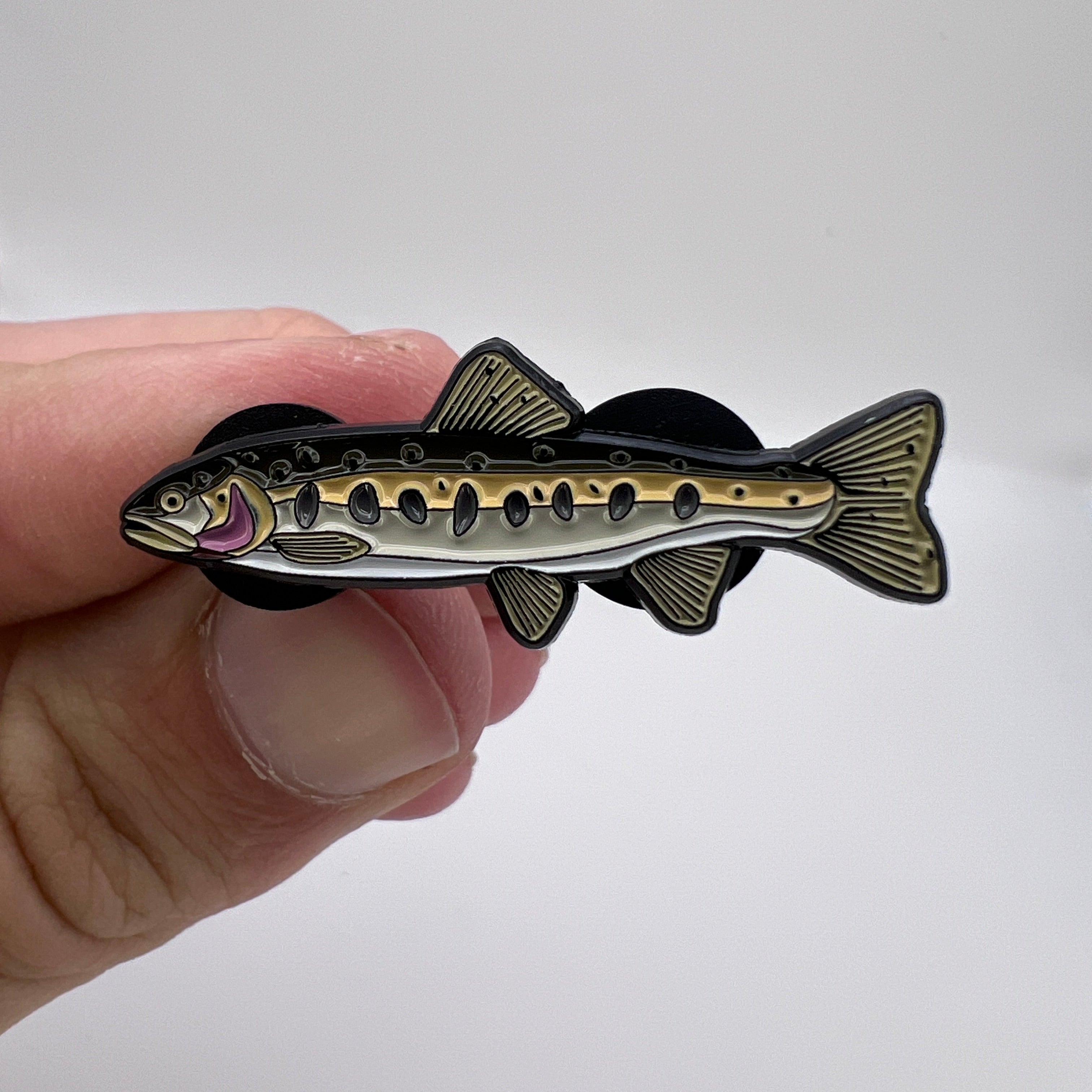 Hand holding a decorative fish-shaped object against a white background