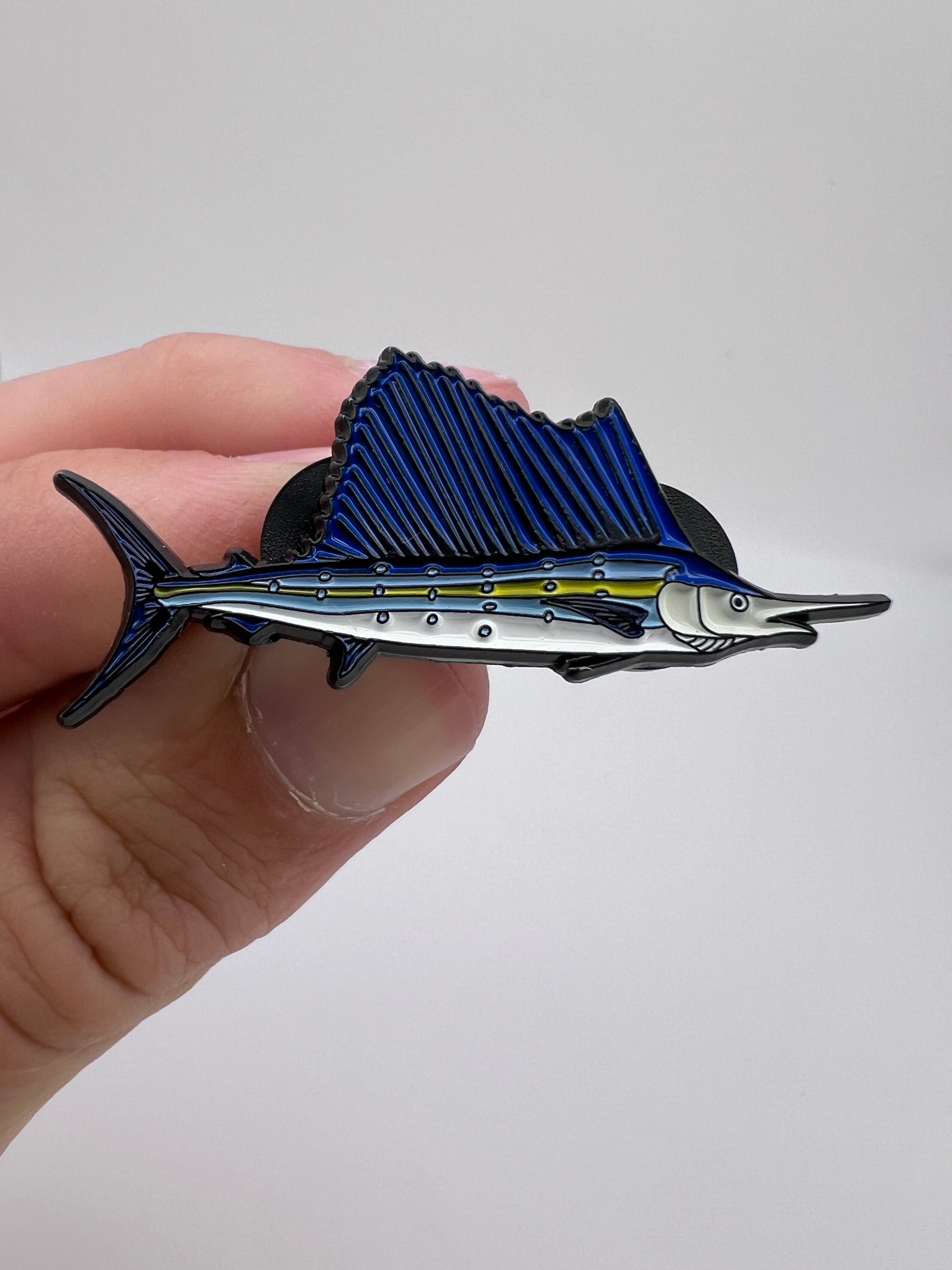Hand holding a blue and silver fish-shaped object against a white background