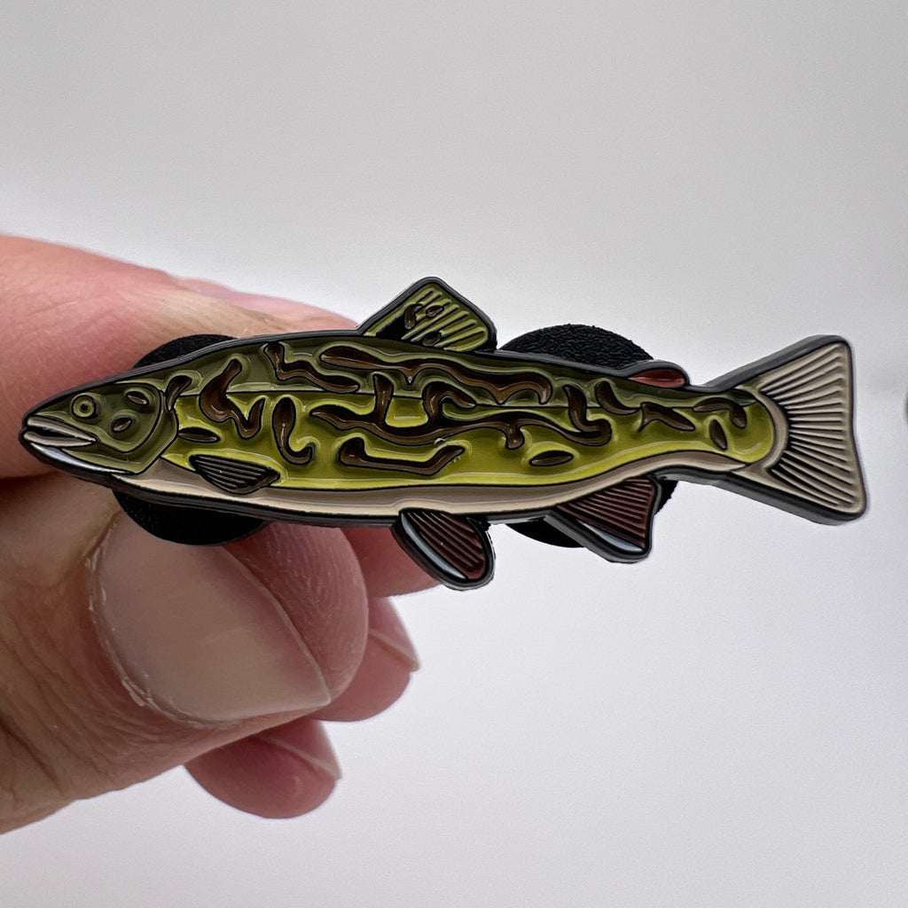 Hand holding a fish-shaped decorative item with intricate patterns on a white background
