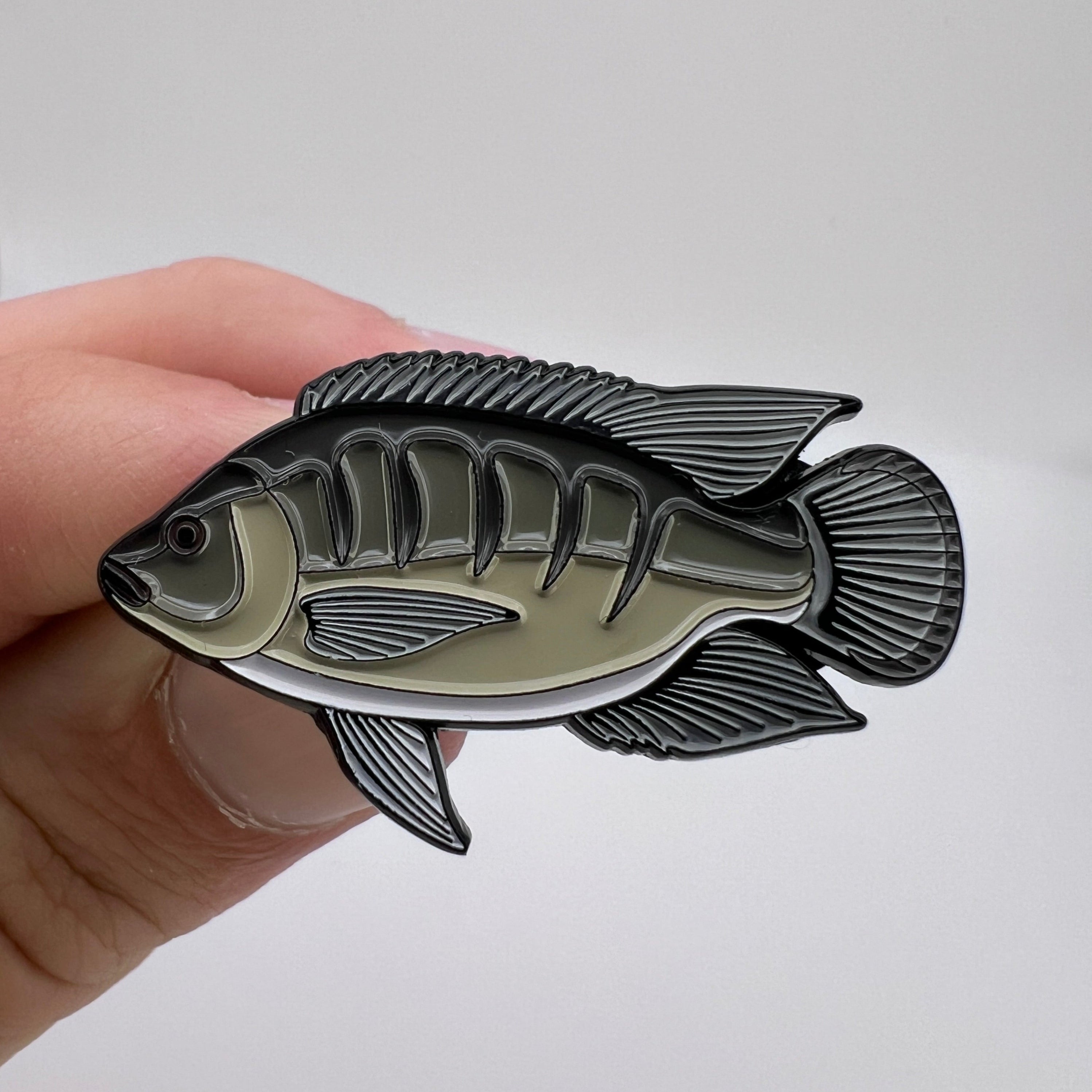 Fish-shaped object held in a hand against a plain background