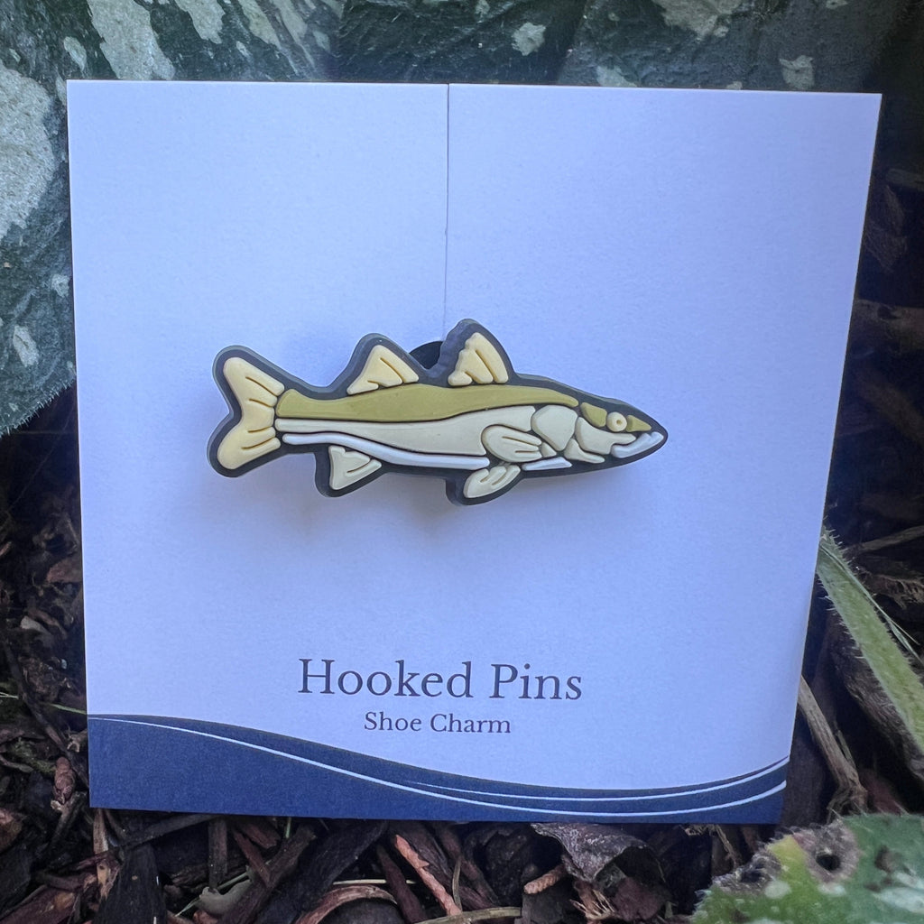 Fish-shaped shoe charm on a card labeled 'Hooked Pins' with a natural background