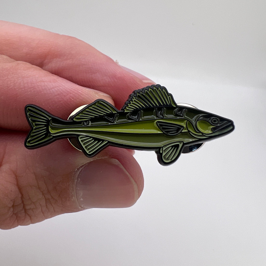 Hand holding a fish-shaped pin against a white background