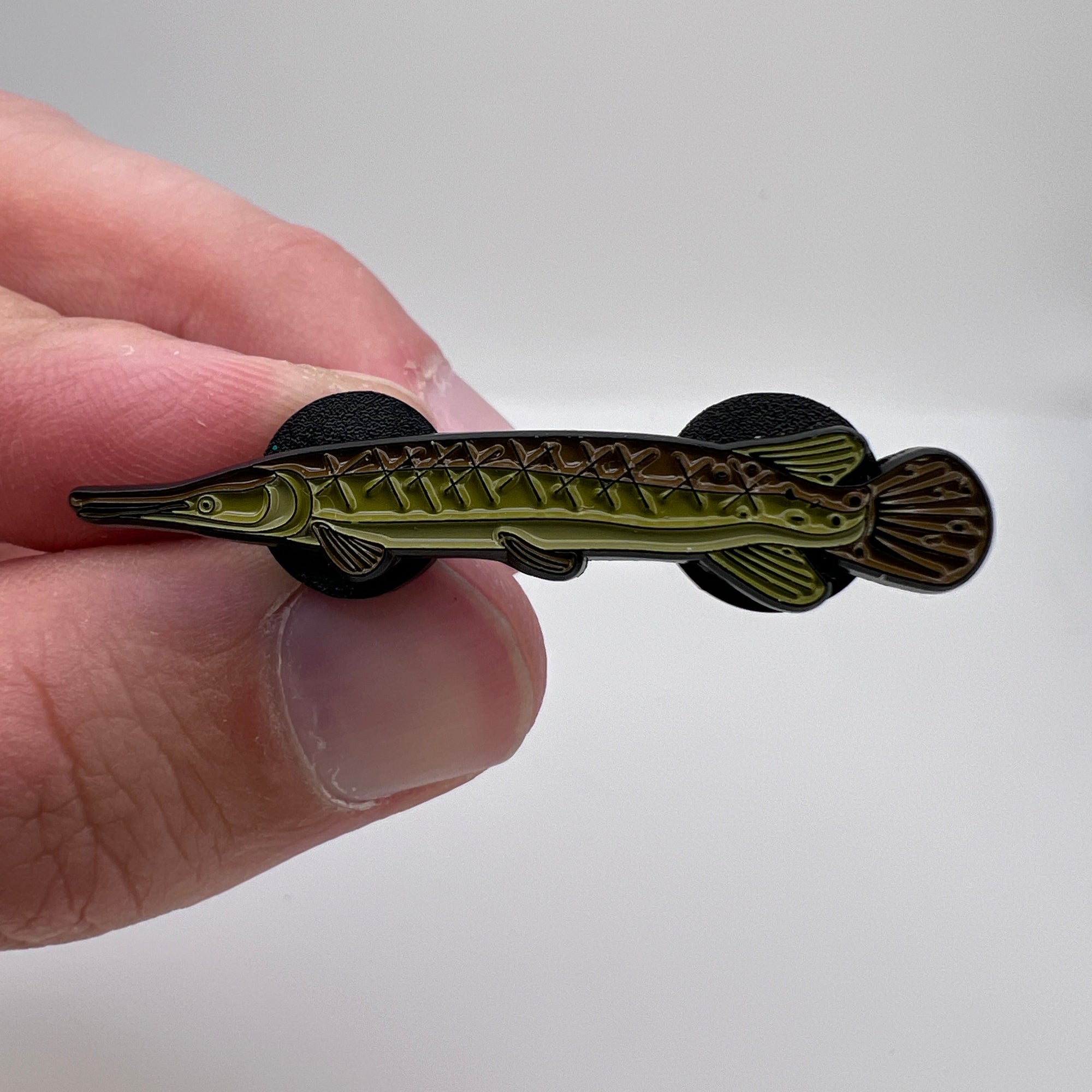 Hand holding a decorative fish-shaped object against a plain background