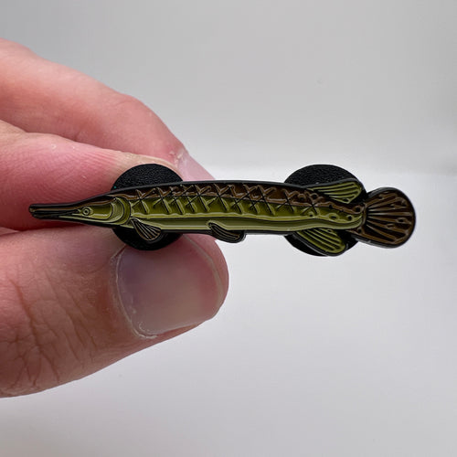 Hand holding a decorative fish-shaped object against a plain background